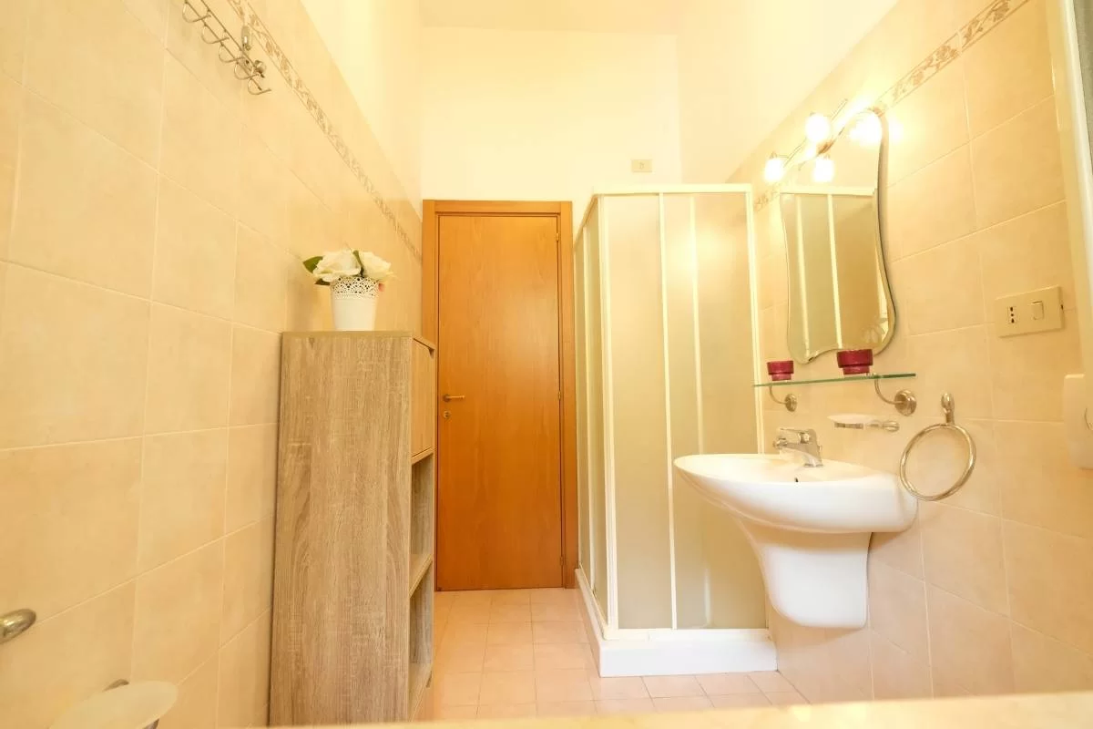 Bagno con doccia, lavandino, specchio e credenza marrone Appartamento Pineto Vacanza Armonia