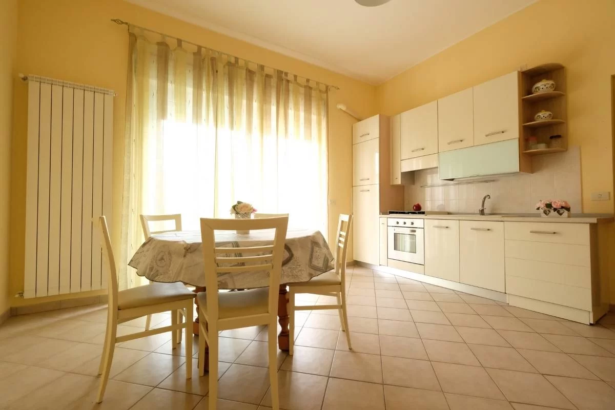 Cucina bianco panna con tavolo e sedie bianche Appartamento Pineto Vacanza Armonia