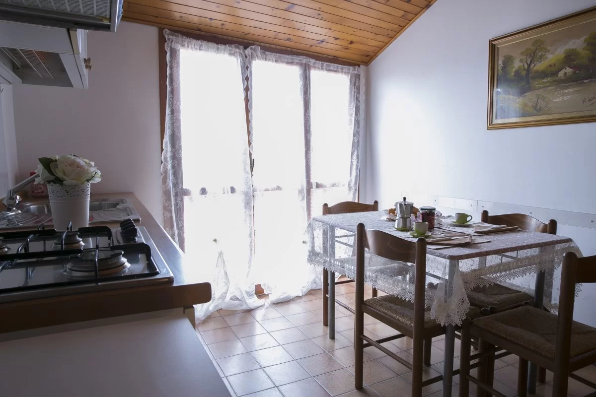 Cucina con tavolo e sedie in legno Appartamento Pineto Vacanza Caterina A2