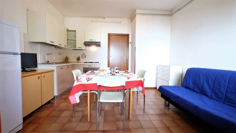 Cucina bianco panna con sofà blu Appartamento Pineto Vacanza Caterina A3