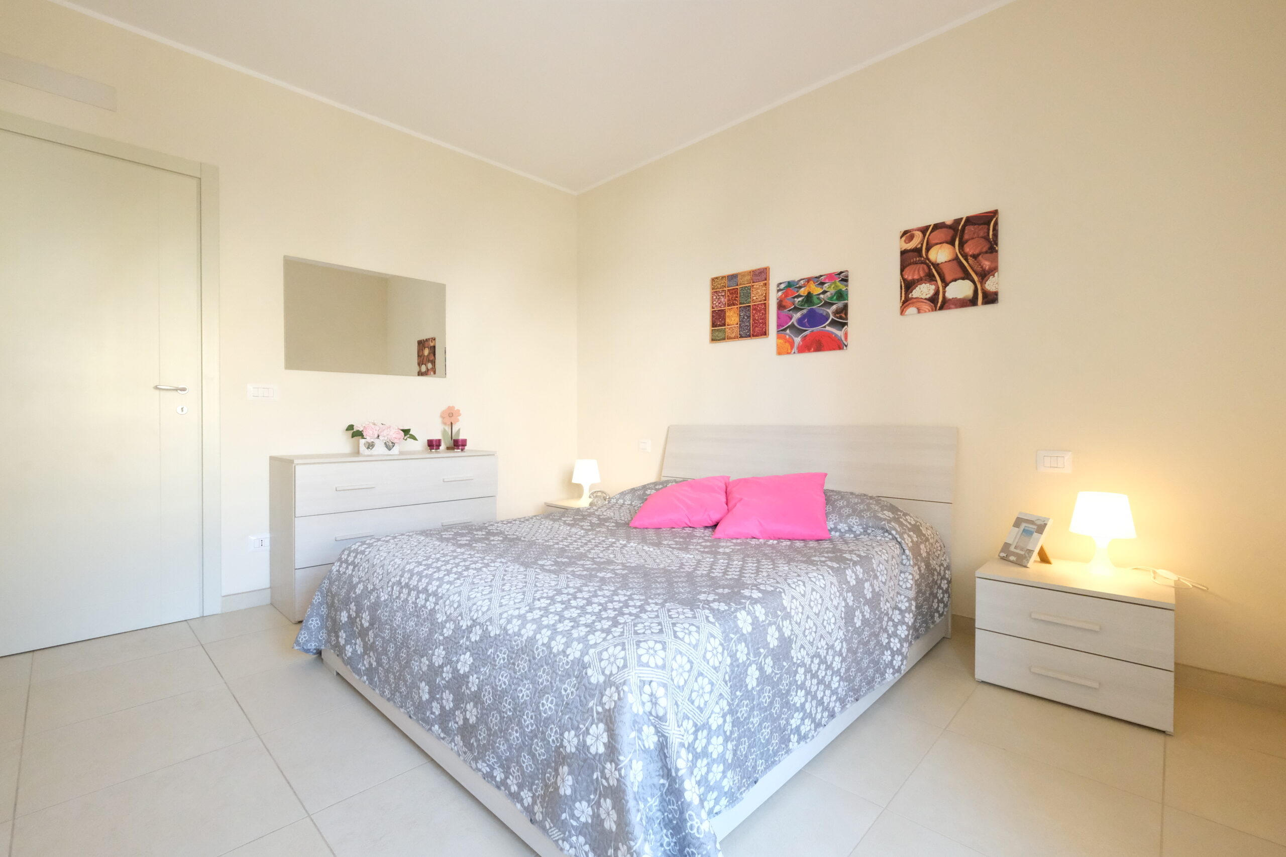 Camera con letto matrimoniale, credenza e comodini beige e quadri colorati Appartamento Pineto Vacanza Residence Claudia int. F