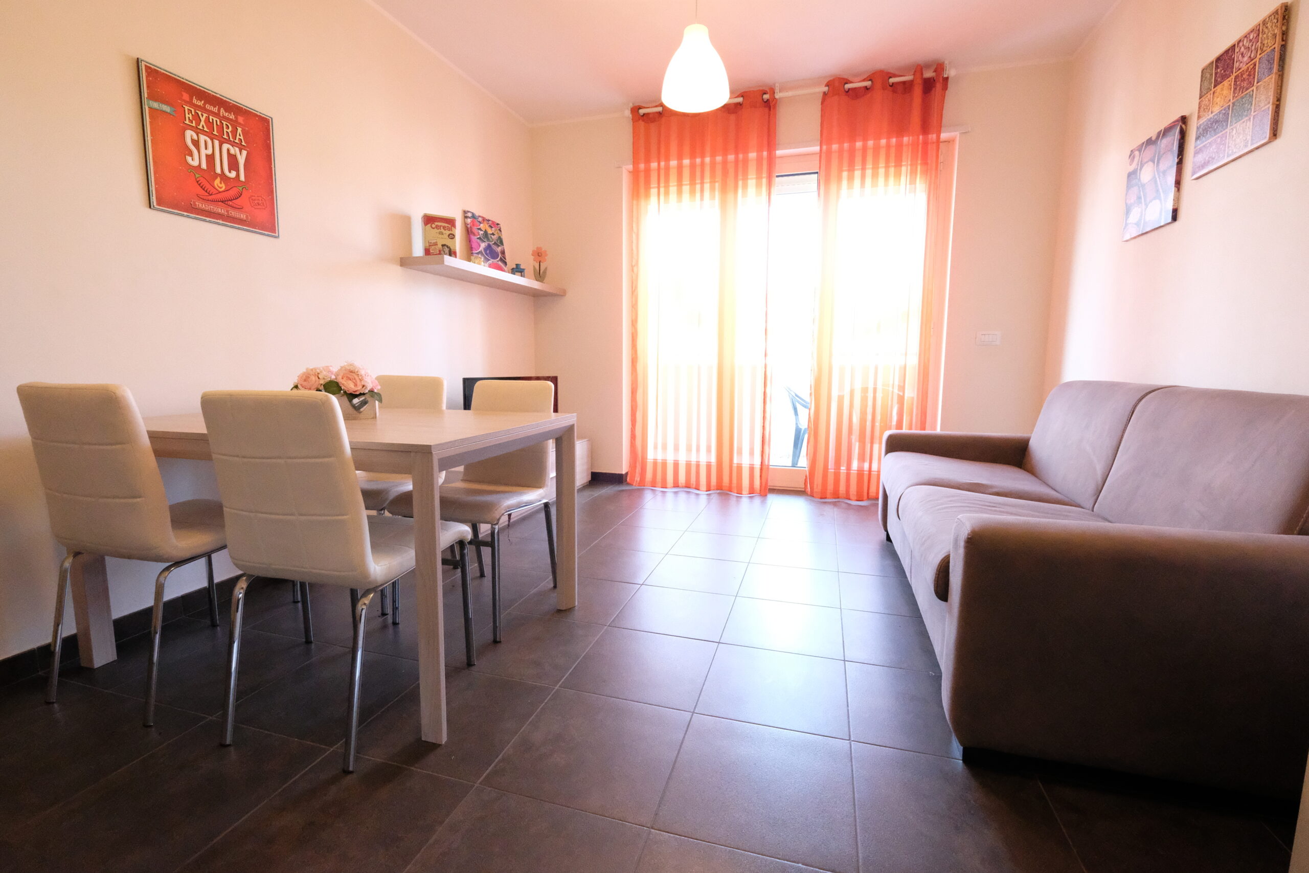 Sala con divano marrone e finestra a porta con tende Appartamento Pineto Vacanza Residence Claudia int. M
