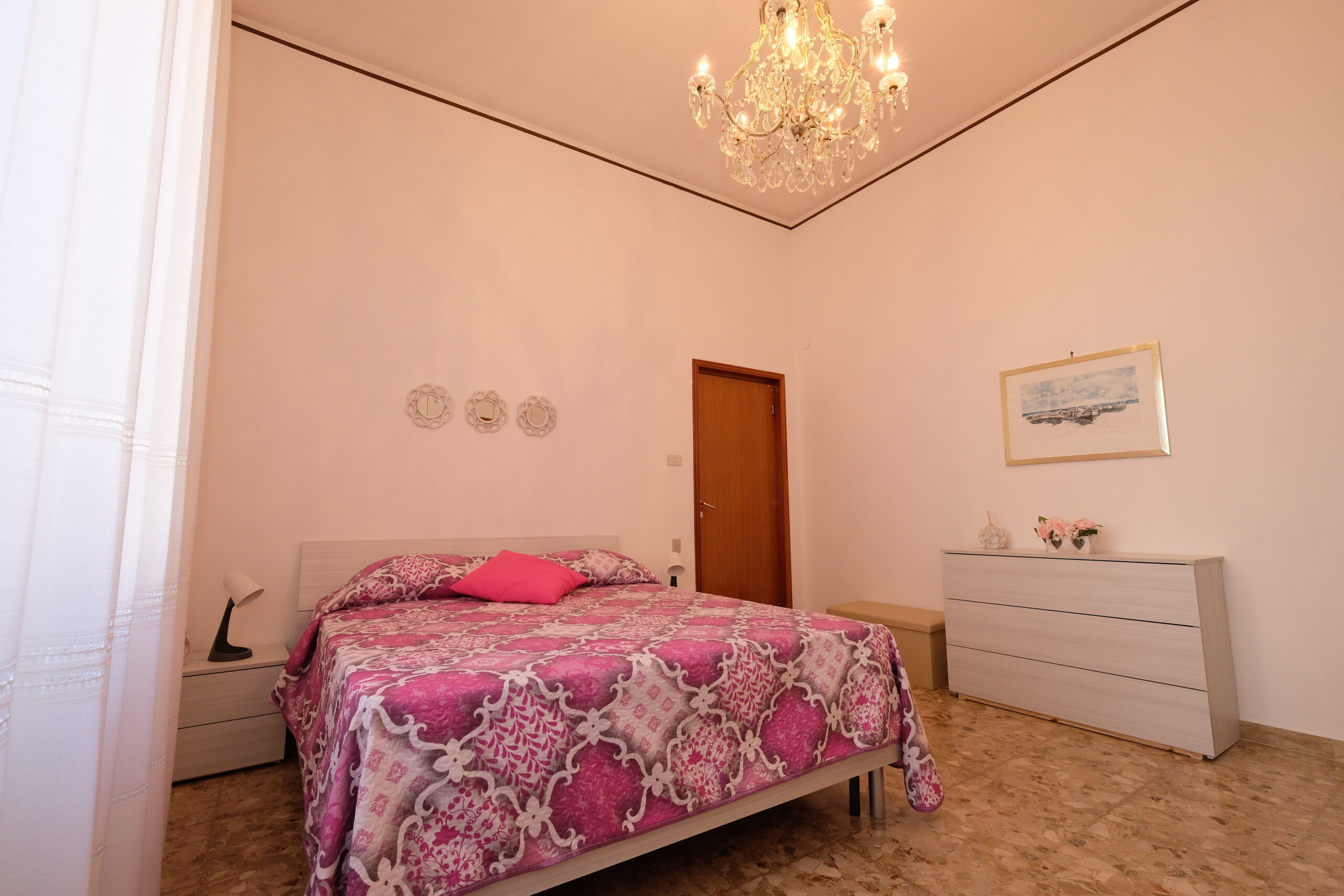 Camera matrimoniale con un comò bianco, un quadro ed un comodino Appartamento Pineto Vacanza Orchidea PT