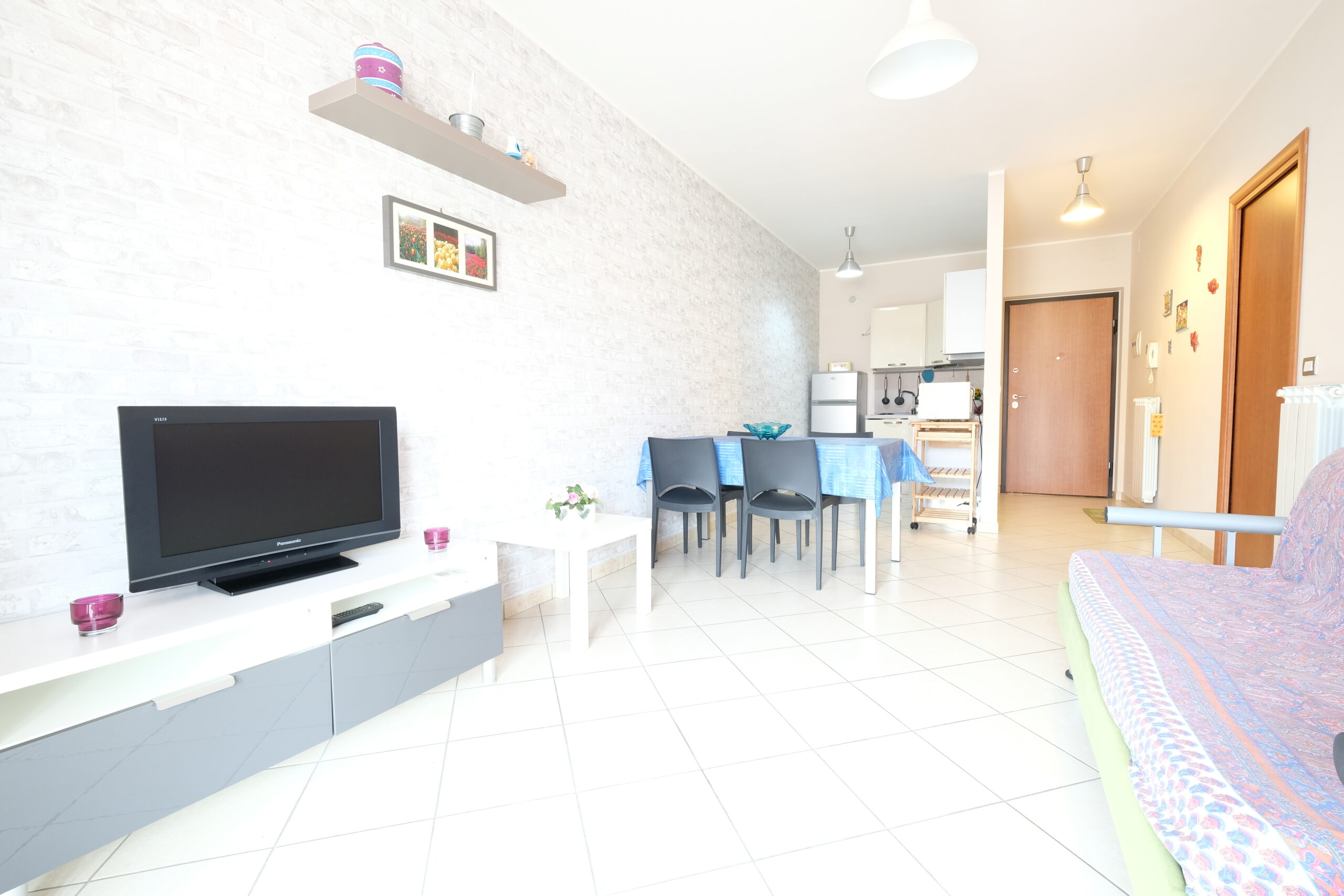 Sala e cucina con televisione e tavolo con sedie Appartamento Pineto Vacanza Poseidon 1