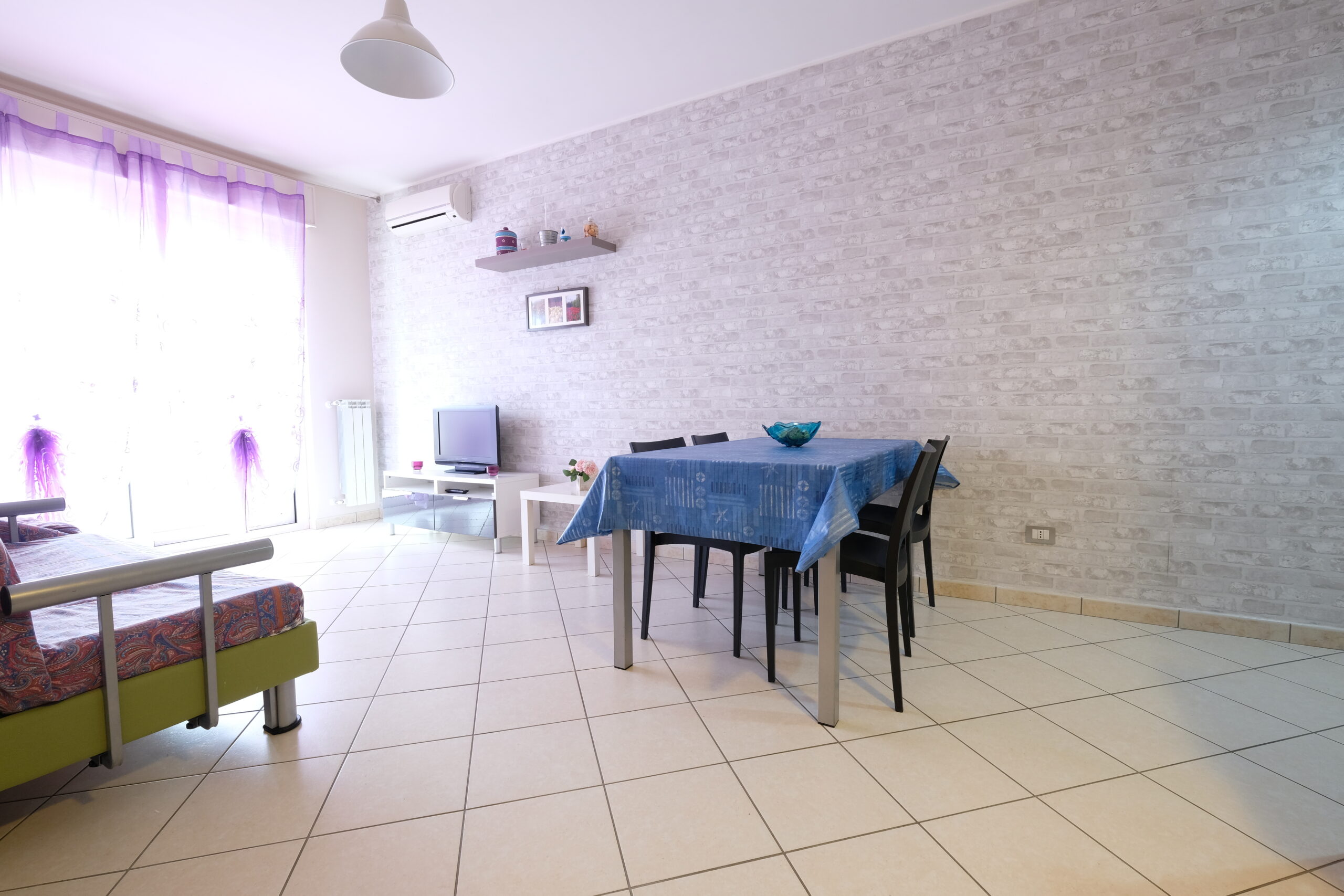 Sala con tavolo, sedie nere e televisione Appartamento Pineto Vacanza Poseidon 1
