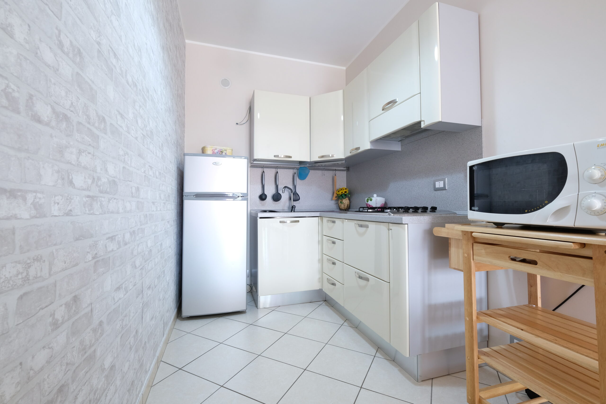 Cucina piccola bianca con frigorifero, microonde e fornelli a gas Appartamento Pineto Vacanza Poseidon 1