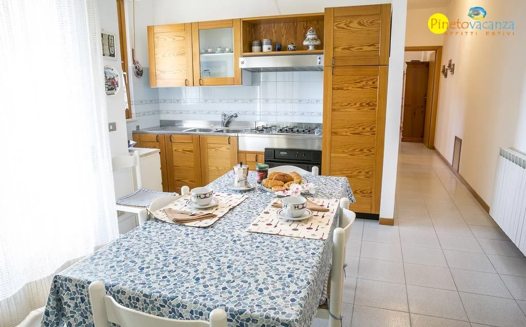 Cucina marrone con tavolo e sedie bianche Appartamento Pineto Vacanza Gemma 2