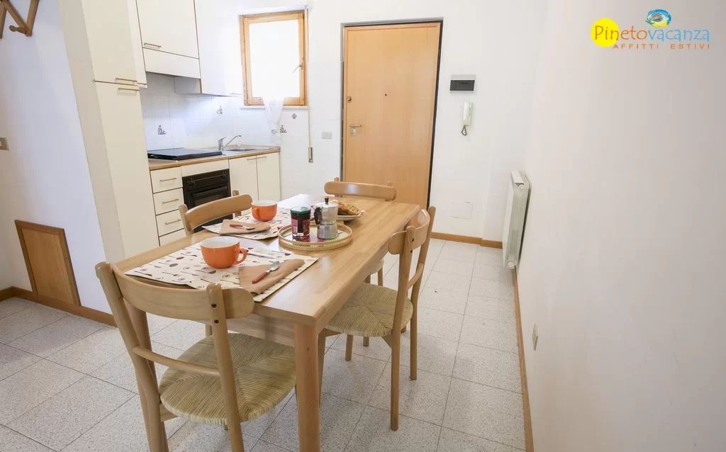 Cucina bianca con tavolo e sedie in legno Appartamento Pineto Vacanza Gemma