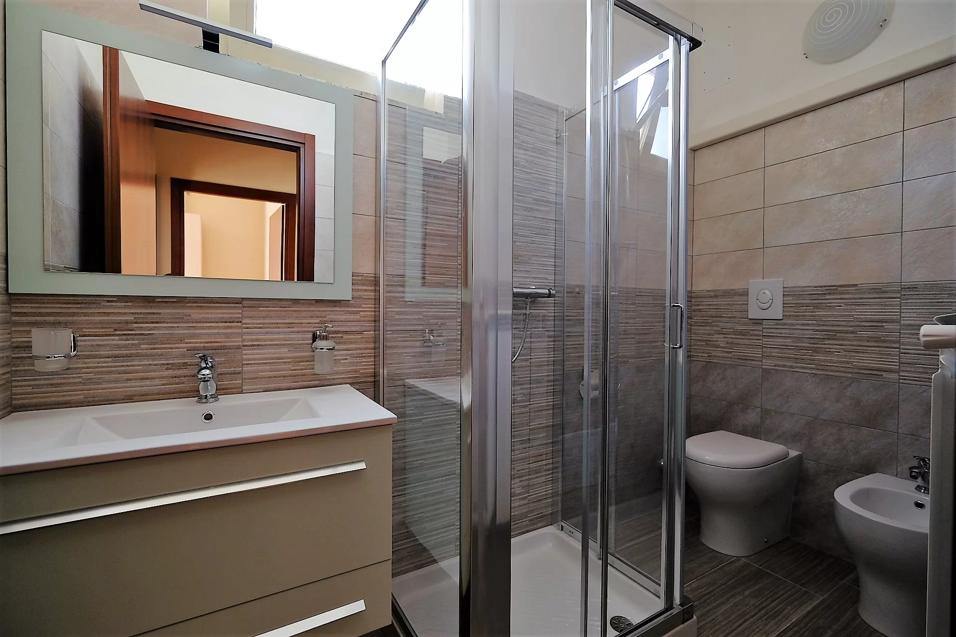 Bagno con specchio, lavandino, doccia, bidet e gabinetto Appartamento Pineto Vacanza Ginevra