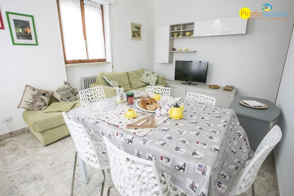 Sala con divani, televisione e tavolo con sedie Appartamento Pineto Vacanza Le Palme 2