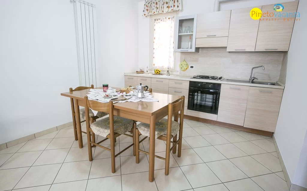 Cucina beige con tavolo e sedie in legno Appartamento Pineto Vacanza Leopardi