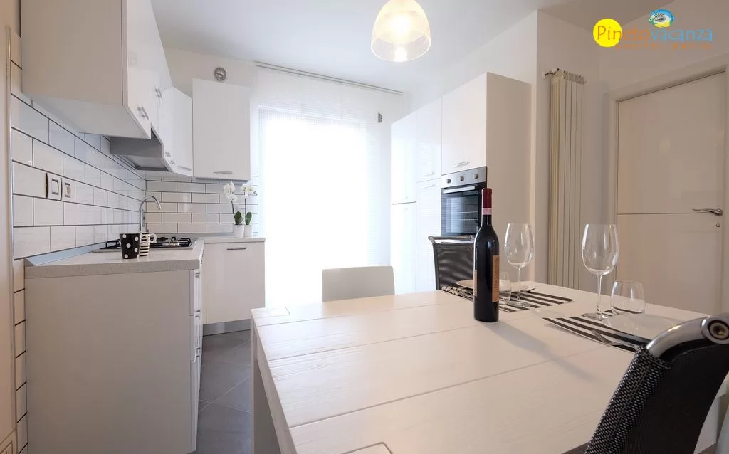 Cucina bianca con tavolo bianco e sedie e finestra Appartamento Pineto Vacanza Mango 2