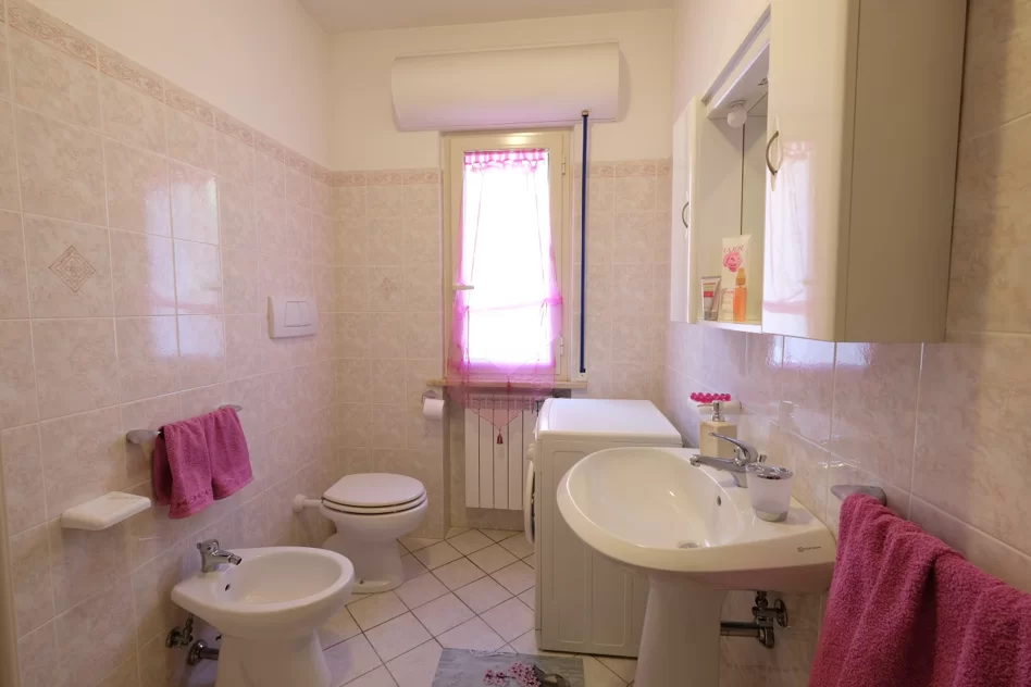 Bagno con lavandino, gabinetto, bidet, lavatrice e credenza con specchio Appartamento Pineto Vacanza Marina
