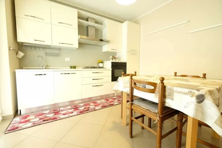Cucina bianca con tavolo e sedie in legno Appartamento Pineto Vacanza Acqua Marina 1