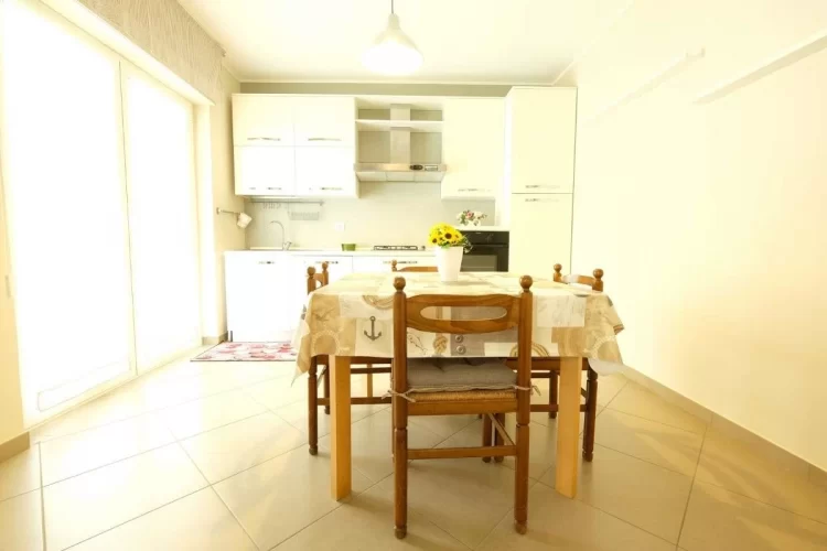 Cucina bianca con tavolo e sedie in legno Appartamento Pineto Vacanza Acqua Marina 1