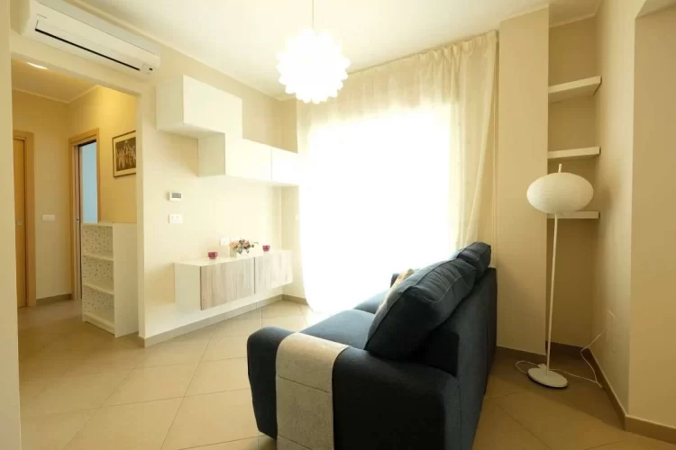 Sala con sofà blu e credenze bianche Appartamento Pineto Vacanza Acqua Marina 1
