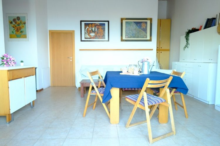 Sala con tavolo e sedie in legno e mobili bianchi Appartamento Pineto Vacanza Caterina Vista Mare