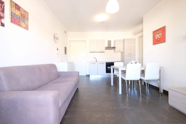 Sala con divano marrone e tavolo con sedie bianche Appartamento Pineto Vacanza Residence Claudia int. M