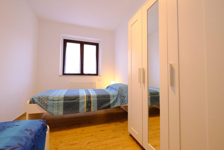 Camera doppia con letti singoli, una finestra e un armadio bianco Appartamento Pineto Vacanza Venere 1