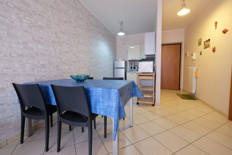 Cucina piccola bianca con tavolo e sedie nere e l'ingresso Appartamento Pineto Vacanza Poseidon 1