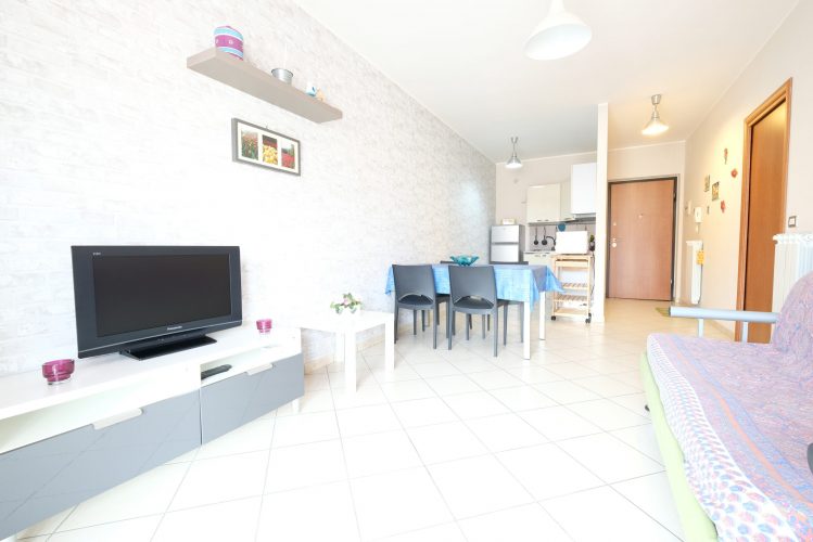 Sala e cucina con televisione e tavolo con sedie Appartamento Pineto Vacanza Poseidon 1