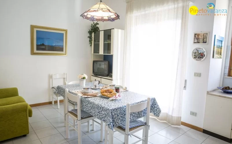 Sala con divano verde e tavolo e sedie bianche Appartamento Pineto Vacanza Gemma 2