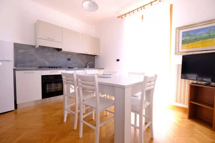Cucina beige chiaro con tavolo e sedie bianche Appartamento Pineto Vacanza Lady