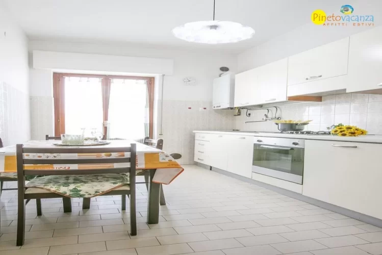 Cucina bianca con tavolo e panche marroni Appartamento Pineto Vacanza Le Palme 2
