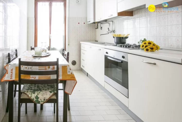 Cucina bianca con tavolo e sedie marroni Appartamento Pineto Vacanza Le Palme 2