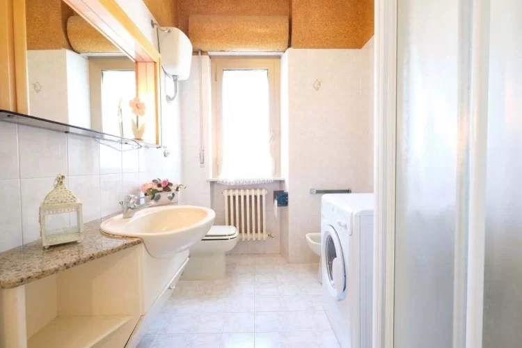 Bagno con lavandino, credenza a specchio, lavatrice, gabinetto e doccia Appartamento Pineto Vacanza Malibù
