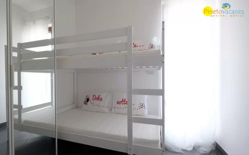 Camera con letto a castello bianco comprendente di una scala Appartamento Pineto Vacanza Mango 2