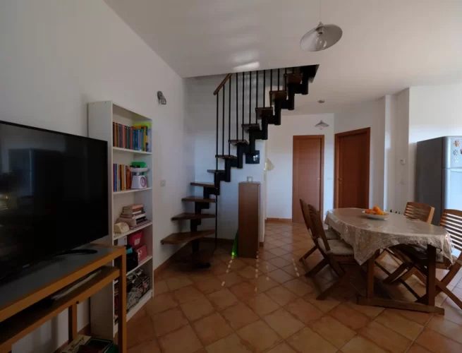 Sala in piano terra con tavolo e sedie di legno e televisione Appartamento Pineto Vacanza Micaene Duplex