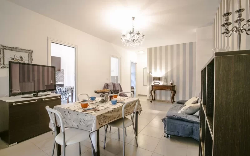 Sala con tavolo e sedie, televisione e mobili marroni Appartamento Pineto Vacanza Myconos Deluxe D3