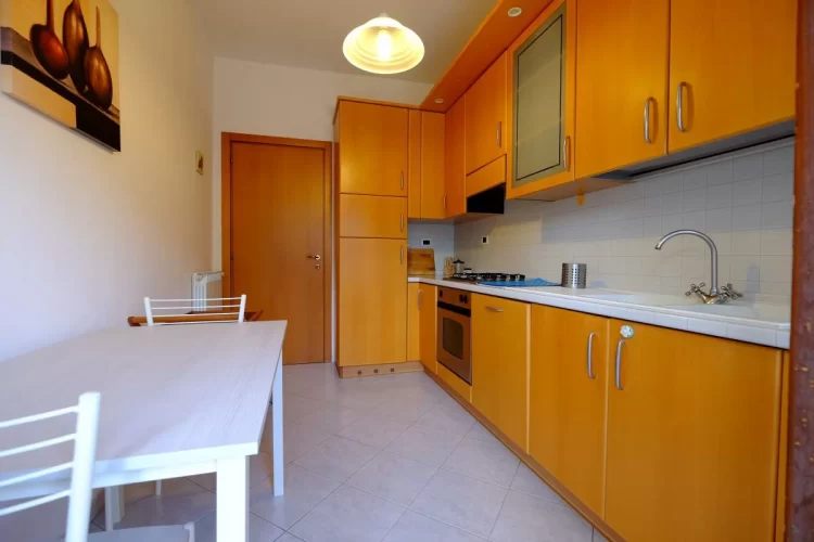 Cucina arancione con tavolo e sedie bianche Appartamento Pineto Vacanza Orchidea 1