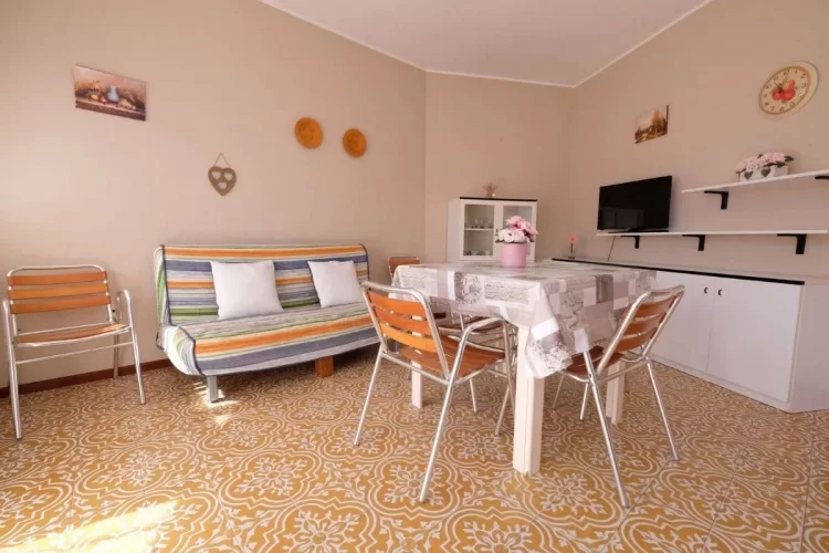 Sala con divano colorato e tavolo con sedie Appartamento Pineto Vacanza Pinetina D2